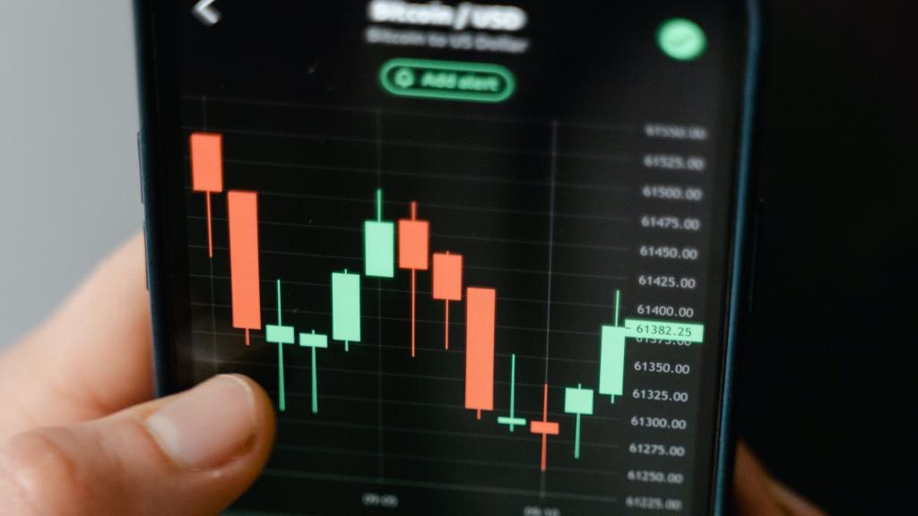 person holding mobile with trading candle stick chart displayed on it